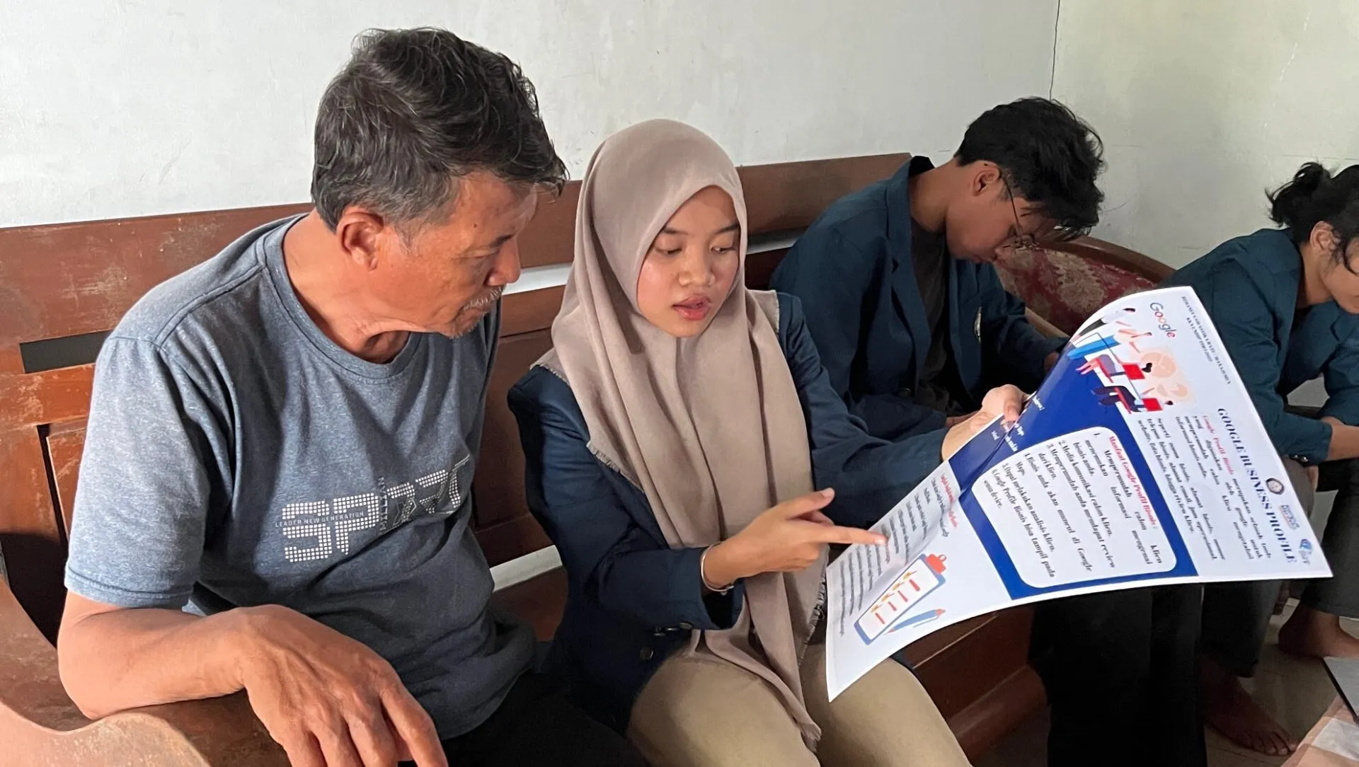 A person and person sitting at a table reading a paper Description automatically generated